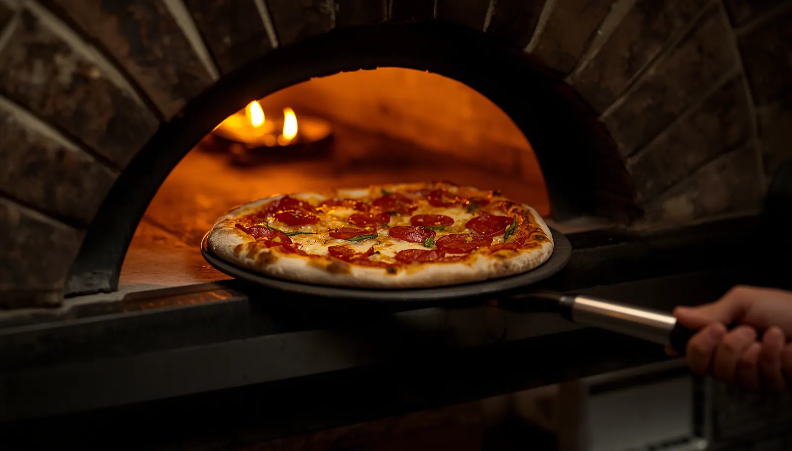 Pizza entrando al horno caliente con llama visible