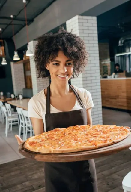 Mesero sirviendo una pizza en la mesa del comedor
